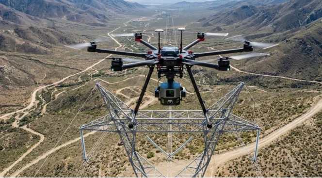 Industrial drone inspecting a high-voltage transmission tower