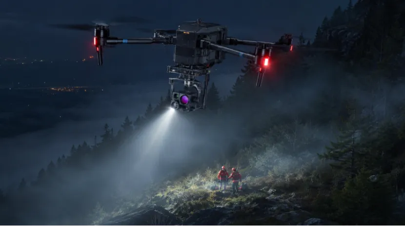 Search and rescue drone with a spotlight flying over foggy mountains at night